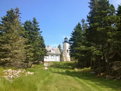 Baker Island in 2012, looking up toward the lighthouse as with the 1937 view, prior to treatment, demonstrating the dense forest characteristic almost obscuring the lighthouse and out buildings from view.