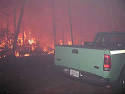 Kabash fire burning at night along a roadside, a Forest Service truck in the forground.