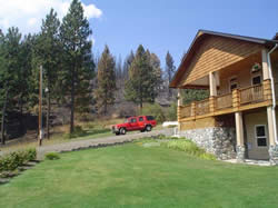 Picture of a residence in the Deer Creek drainage, showing thinned forest in the background that the Poe Cabin fire burned with no damage to the residence.