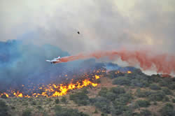 A small plane drops fire retardent along the fire's edge of the Moon Canyon Fire.