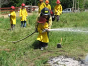 Students dressed up in firefighter gear try suppression tactics on a practice fire.