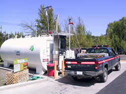 A fuels technician filling a slash fuel tank in a pickup truck.