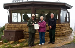 Sandra Kellogg presenting the historic listing to Larry Wiese and Alan Farnsworth in front of the Park Point Lookout.