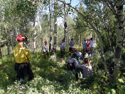 SCA volunteer Kyle Cannon (left, in Nomex) listens as Engine 3 engine lead Jon White briefs the Youth Conservation Program crew before working on a fuels reduction project at Shadow Mountain.