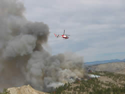Helicopter flying over a burn area.