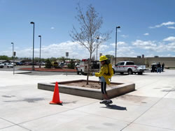 A child dressed in fire clothing and a hardhat squirting balls off of a traffic cone with a back pack pump (bladder bag).