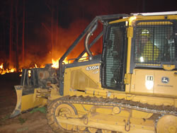 Tractor operating at night along an active fireline.