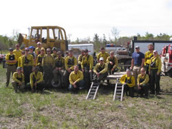 Refuge and fire staff from several refuges posing in front of firefighting equipment.