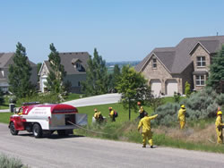 Firefighters doing fire suppression around houses in the subdivision.